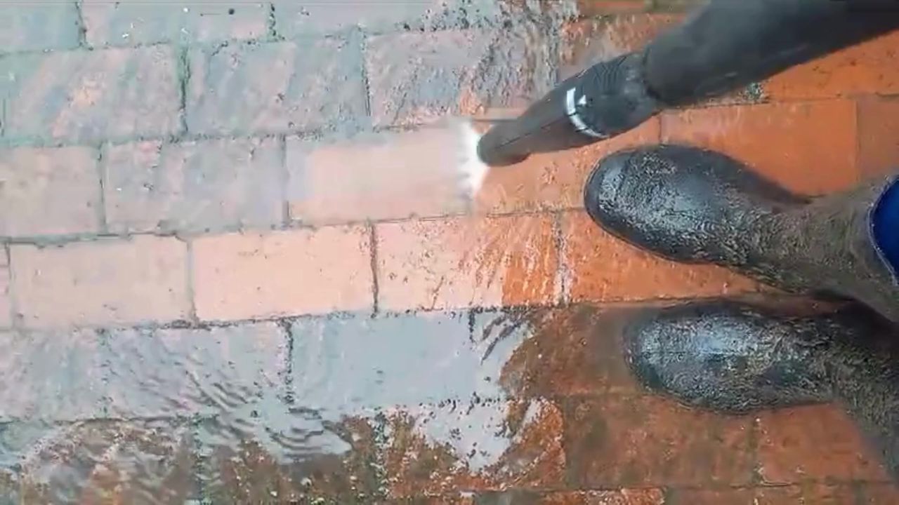 A clean red stripe cut through grey, dirty brick paving